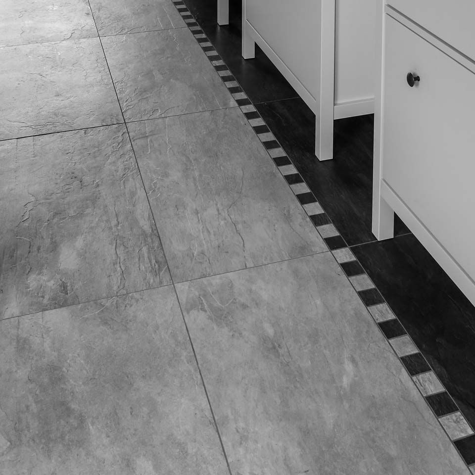 Gefliester Boden mit schwarz-weißem Rand entlang einer Reihe weißer Schränke.