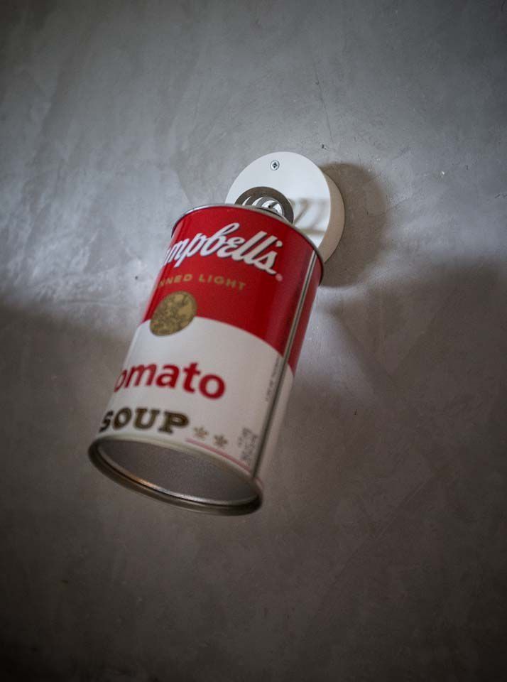 Campbell's Tomatensuppendose schräg gestellt, rot-weißes Etikett auf grauem Untergrund.