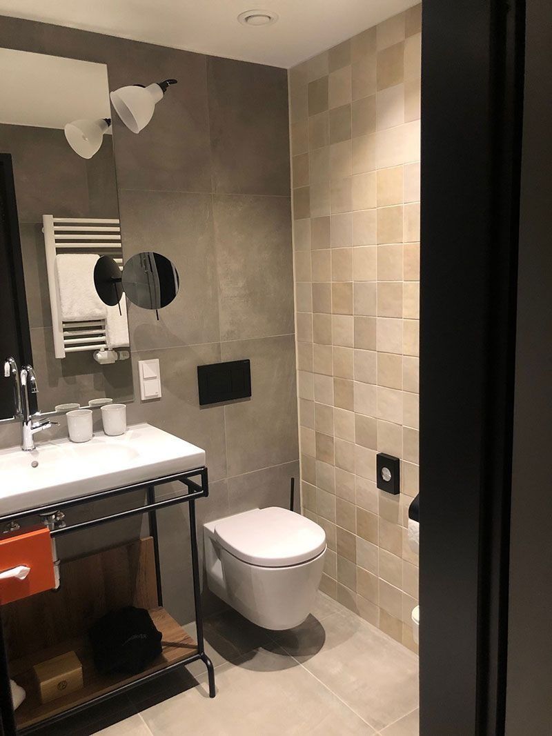 Badezimmer mit Waschbecken, Toilette und gefliesten Wänden; neutrale Farbtöne.