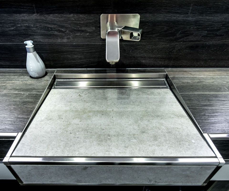 Modernes Badezimmerwaschbecken mit grau gesprenkelter Oberfläche, silberner Armatur und Seifenspender.