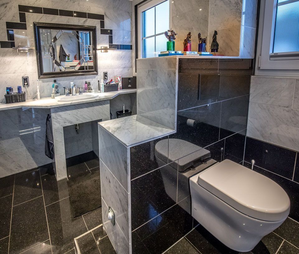 Luxuriöses schwarz-weißes Badezimmer mit Marmorarbeitsplatte und moderner Toilette.