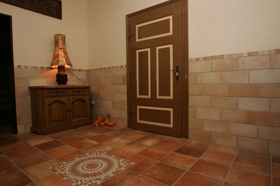 Flur mit brauner Tür, Schrank, gemustertem Fliesenboden und einer eingeschalteten Lampe.