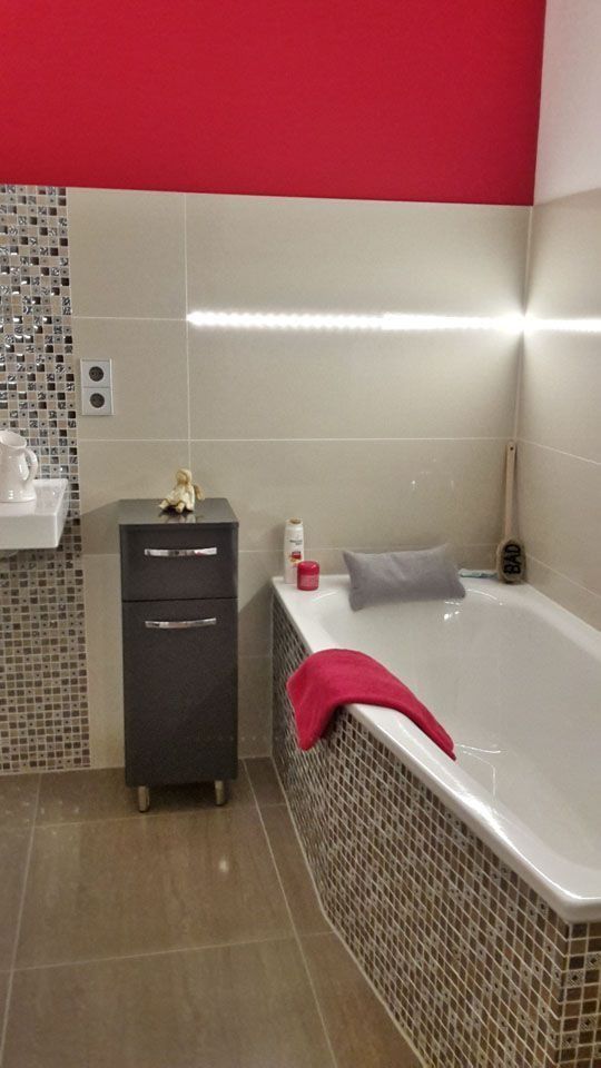 Modernes Badezimmer mit roter Wand, beigefarbenen Fliesen, Mosaikakzenten, Badewanne und dunkelgrauem Schrank.