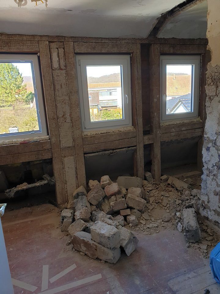Das Zimmer befindet sich im Umbau und weist freiliegende Balken, Fenster und Bauschutt auf.