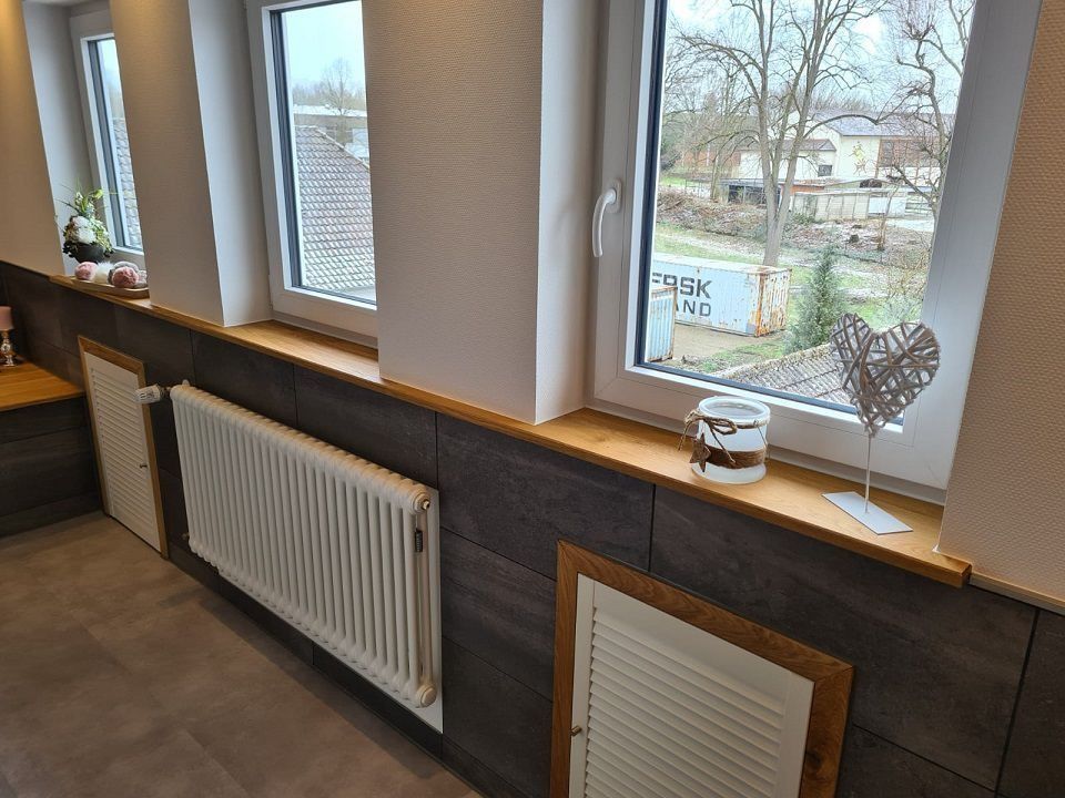 Fensterbank mit Heizkörpern und Holzelementen. Außenansicht eines Hofes und von Gebäuden.