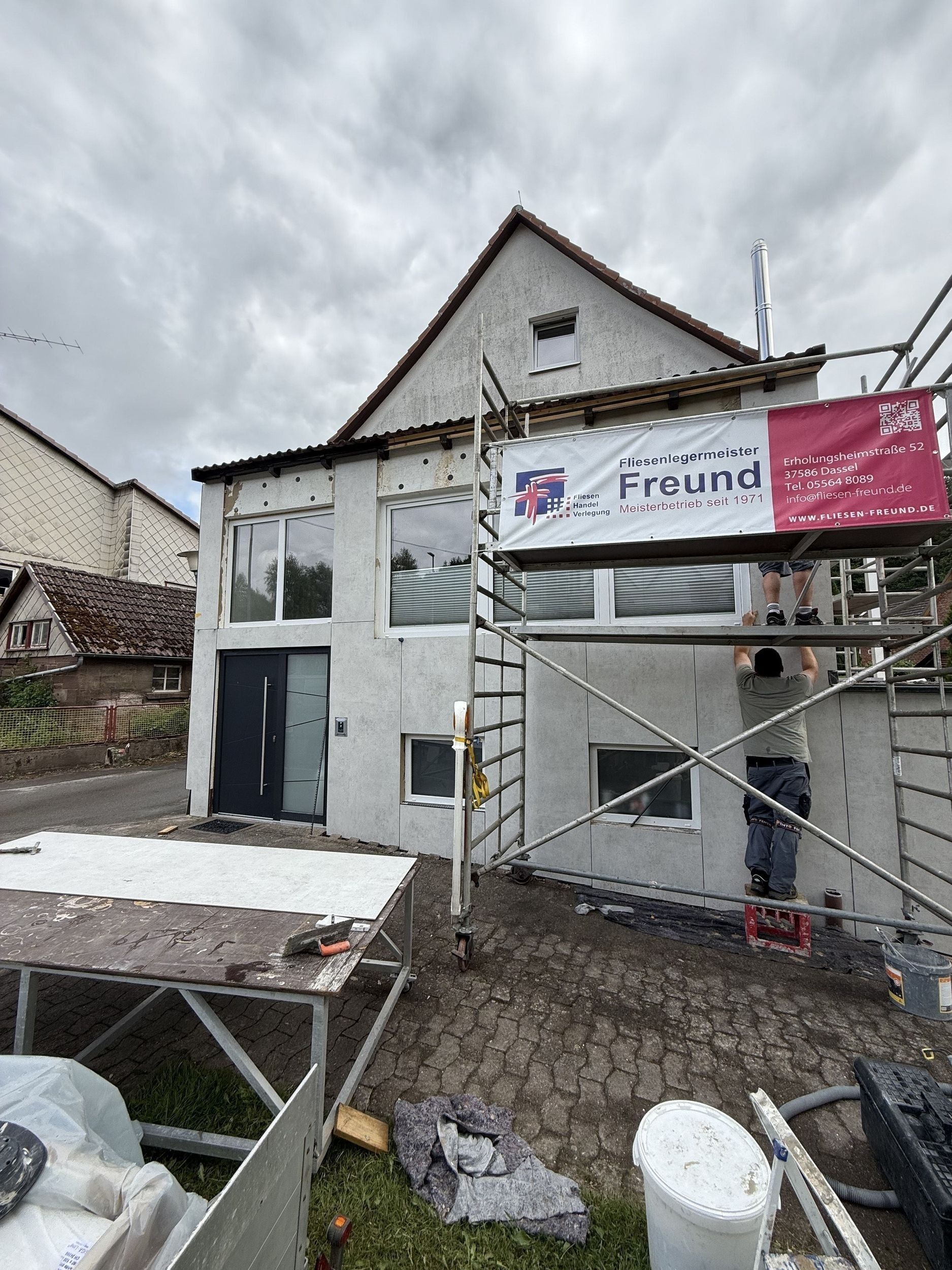 Gebäudeaußenfassade im Bau, Gerüst vorhanden. Person auf dem Gerüst. Grauer Himmel.