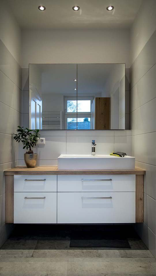 Modernes Badezimmer mit weißem Waschbecken, großem Spiegel und Waschtisch aus Holz und Weiß.