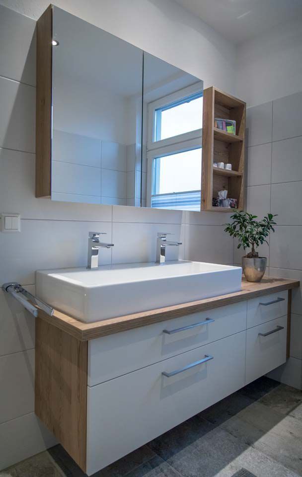 Modernes Badezimmer mit weißem rechteckigem Waschbecken, Spiegelschrank und Holzelementen.