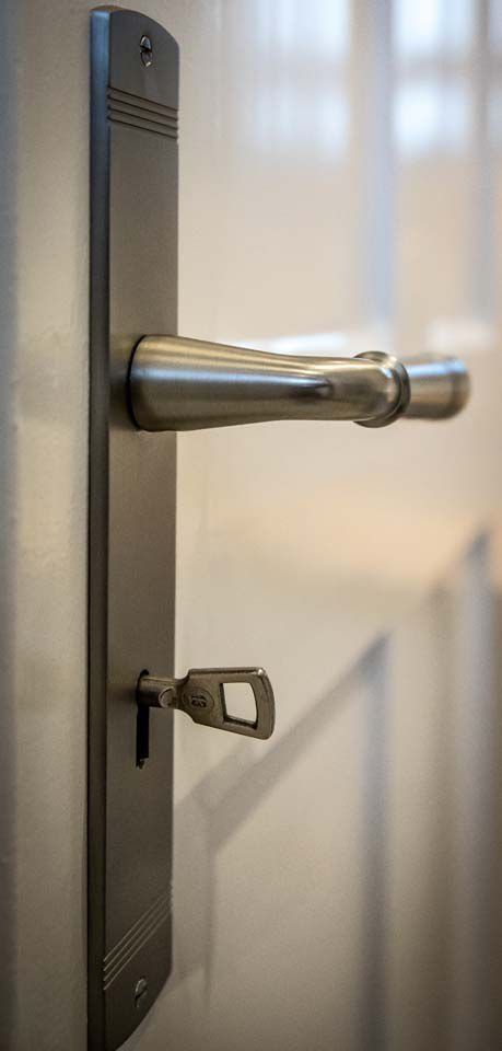 Türgriff mit einem im Schloss steckenden Schlüssel. Silberner Griff an einer weißen Tür.