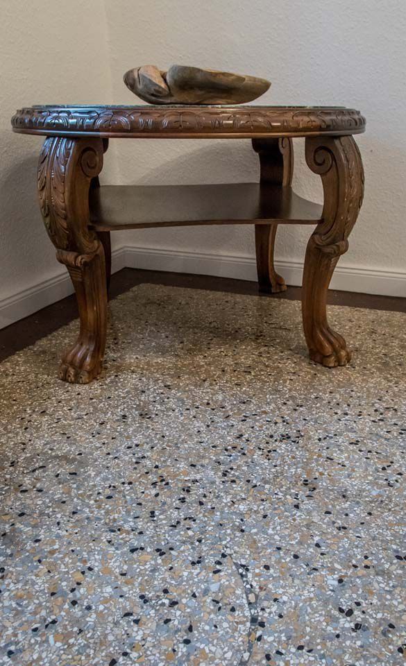 Verzierter Beistelltisch aus Holz mit geschnitzten Details, einem unteren Ablagefach und einer Steinschale darauf.