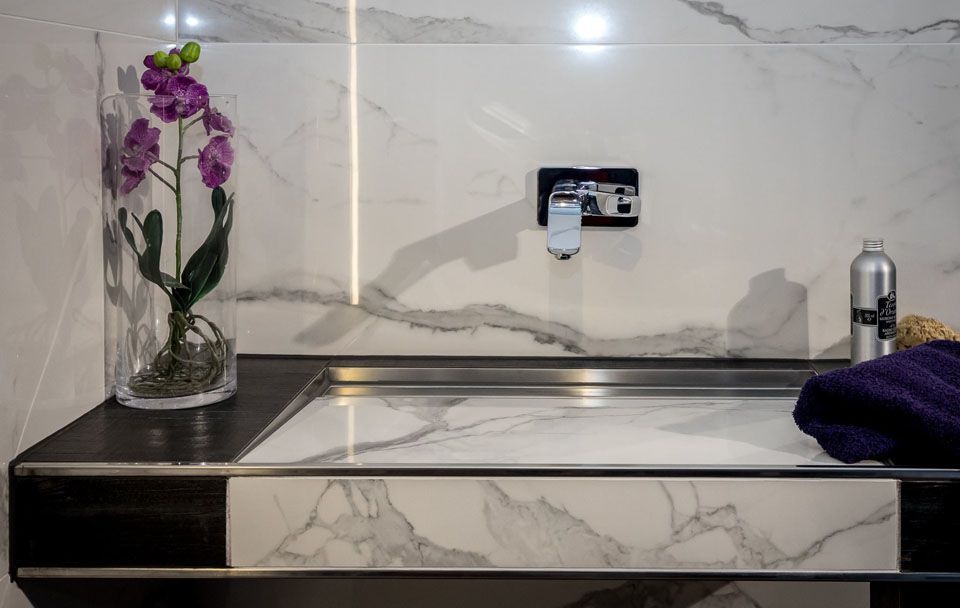 Modernes Badezimmerwaschbecken mit Marmordetails und Orchidee in Vase.