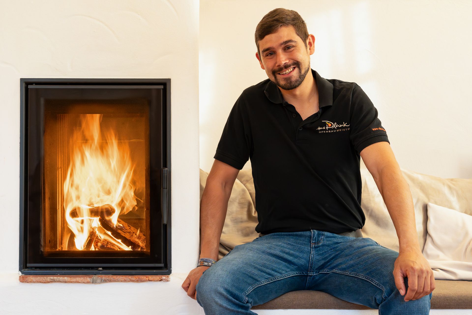 Das Team sitzt neben einem modernen Kamin im Zimmer – von Ofenbau Plank.
