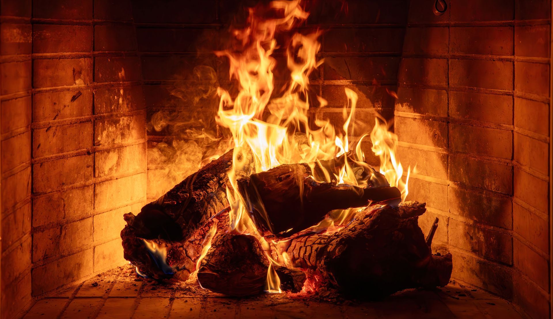 Une cheminée crépitante aux flammes orange vif brûlant des bûches empilées dans un foyer en briques.