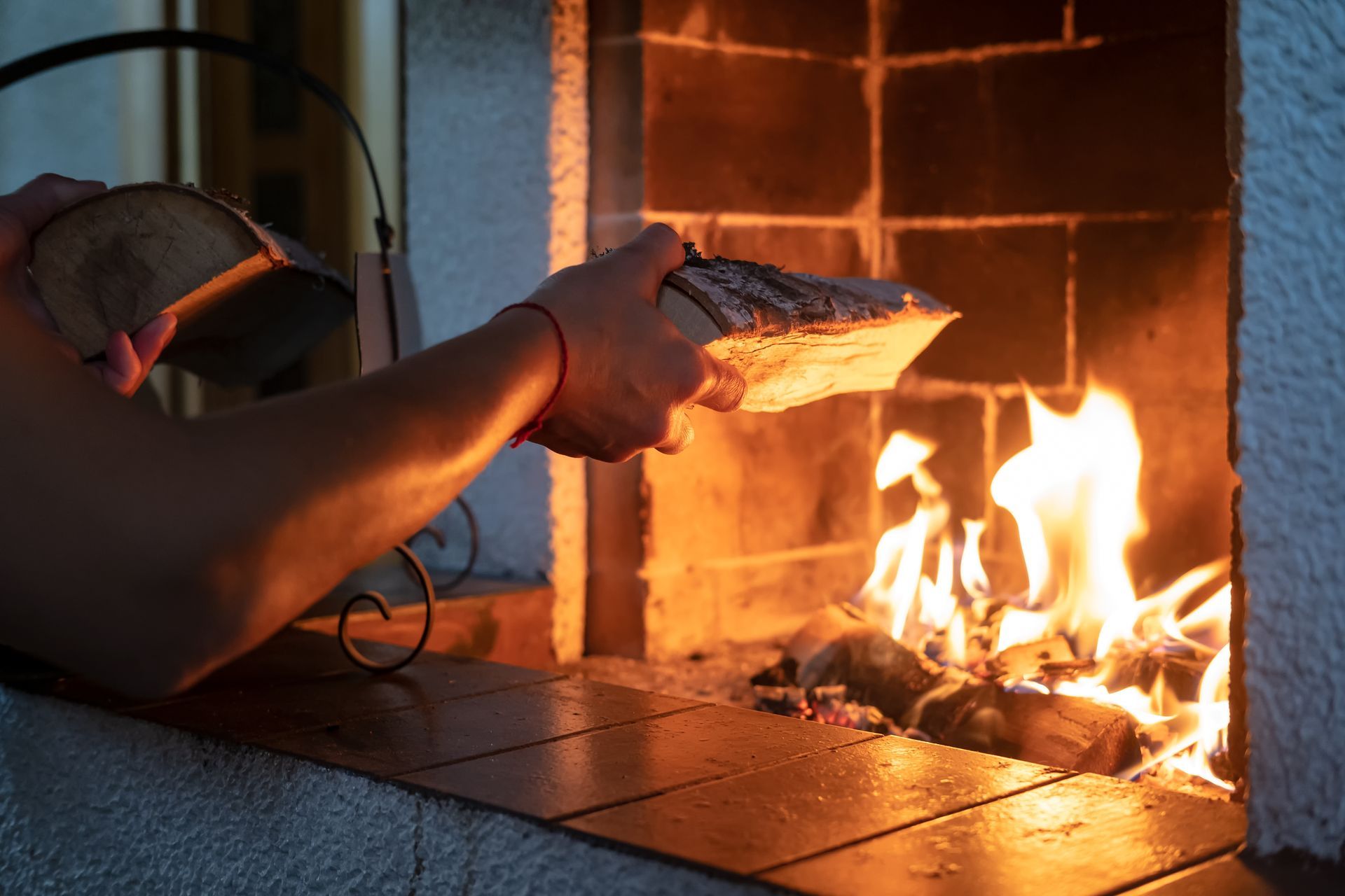 Personne tenant un poisson au-dessus d'un feu dans un four extérieur en briques