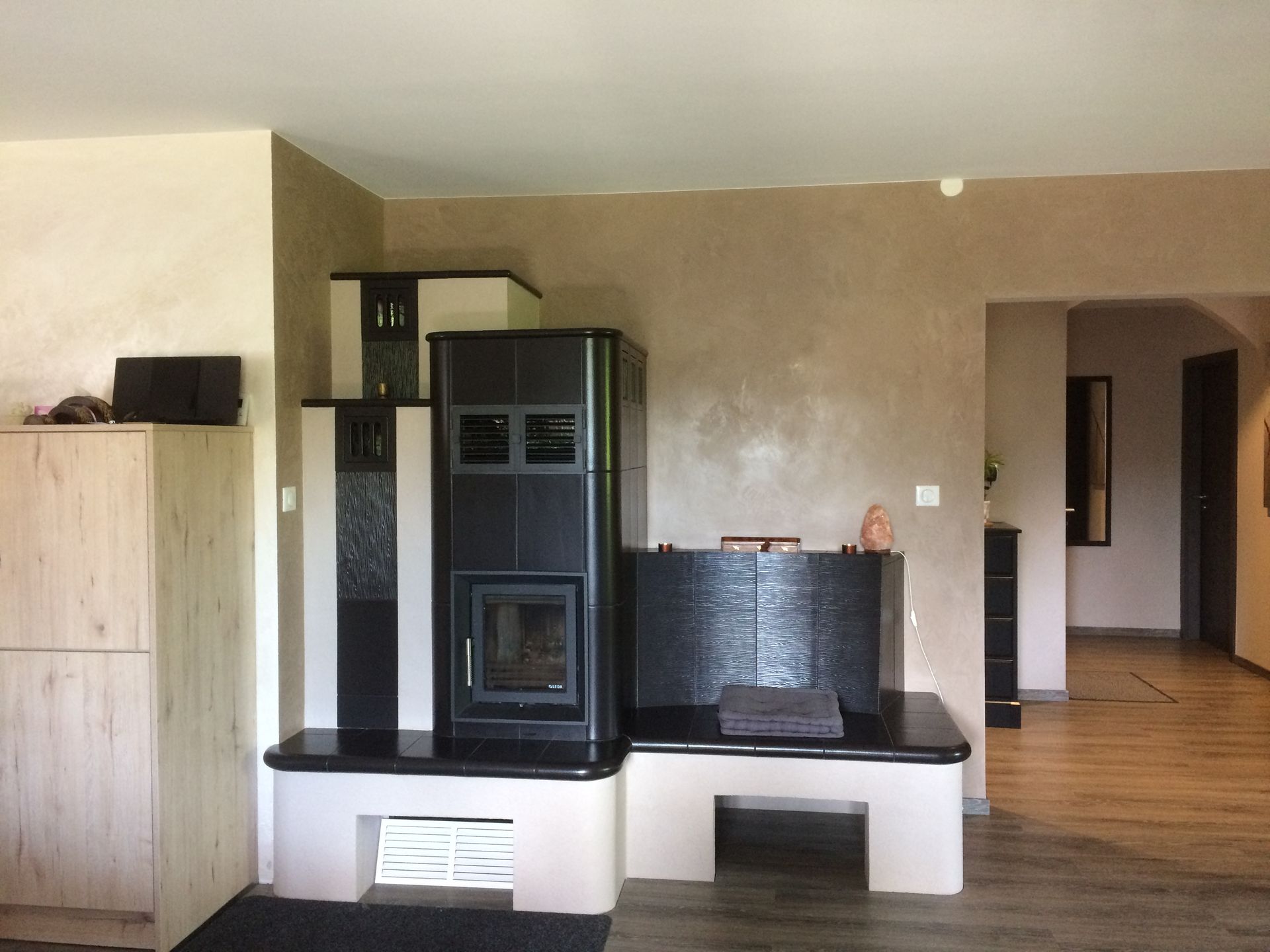 Salon avec cheminée noire, parquet et murs beiges