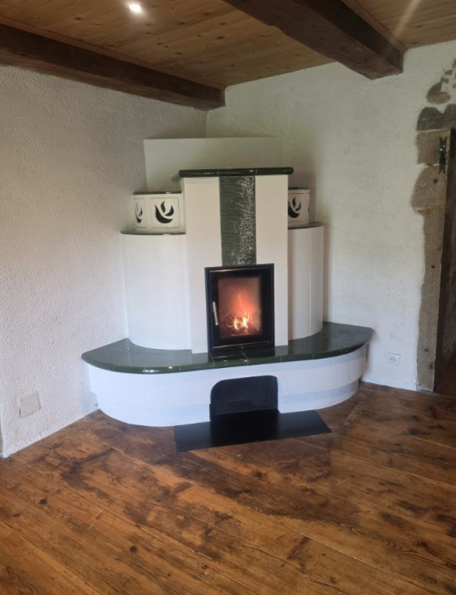 Pièce chaleureuse avec parquet, murs blancs et un poêle à bois noir moderne installé dans un coin de la cheminée.