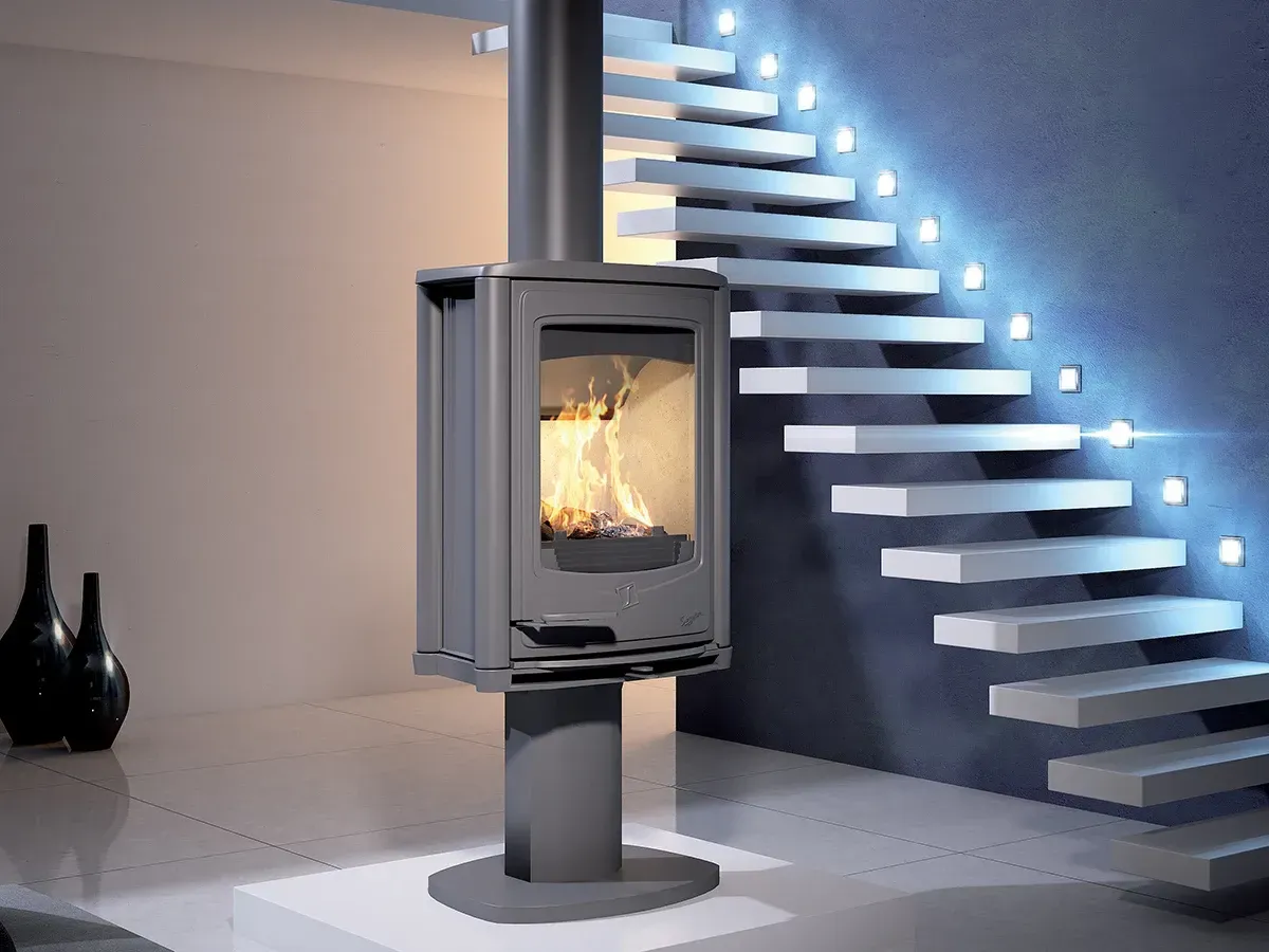 Poêle à bois noir moderne dans une pièce minimaliste, à côté d'un escalier éclairé