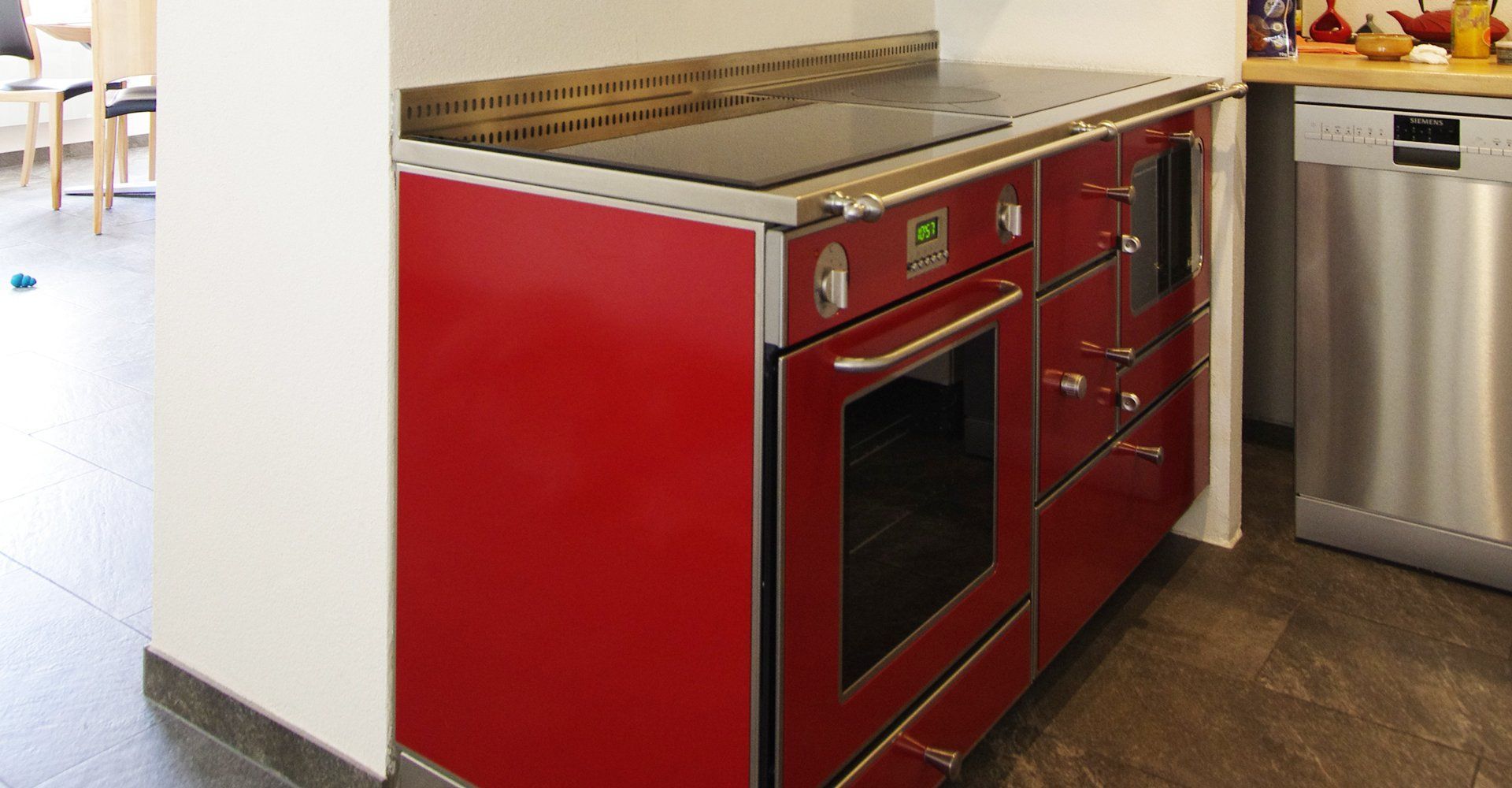 Cuisinière rouge avec four à côté d'un lave-vaisselle en acier inoxydable dans un coin cuisine moderne