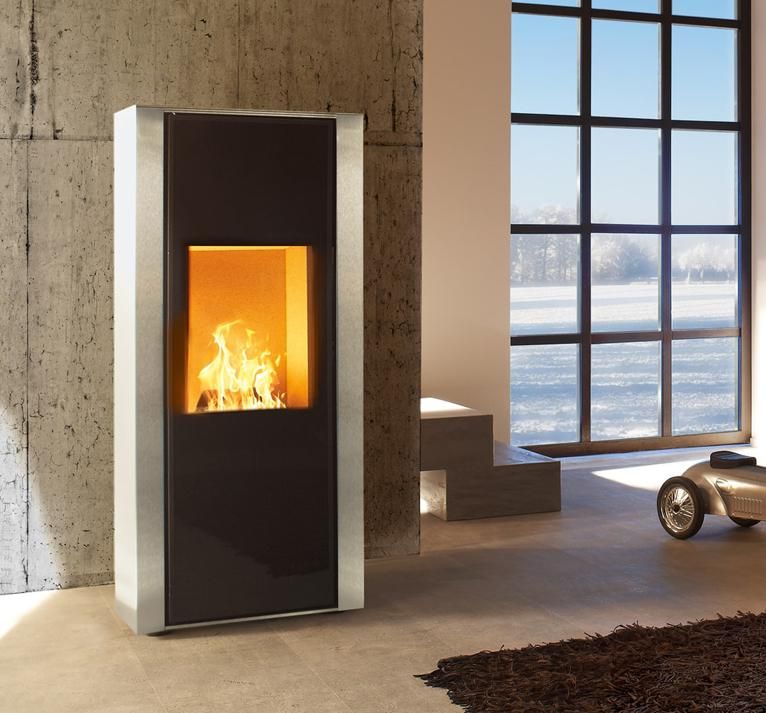 Salon moderne avec une haute cheminée noire qui brûle près d'une grande fenêtre donnant sur l'eau