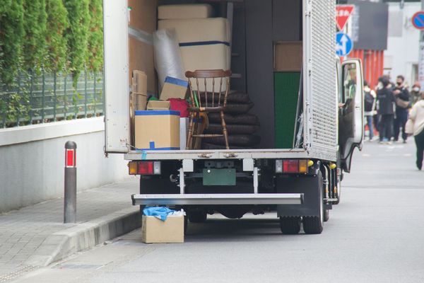 Zwei Personen räumen Kartons in einen Transporter