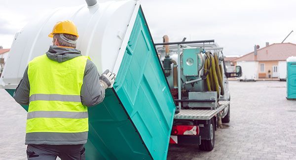 Un homme installant des WC chimiques sur un camion