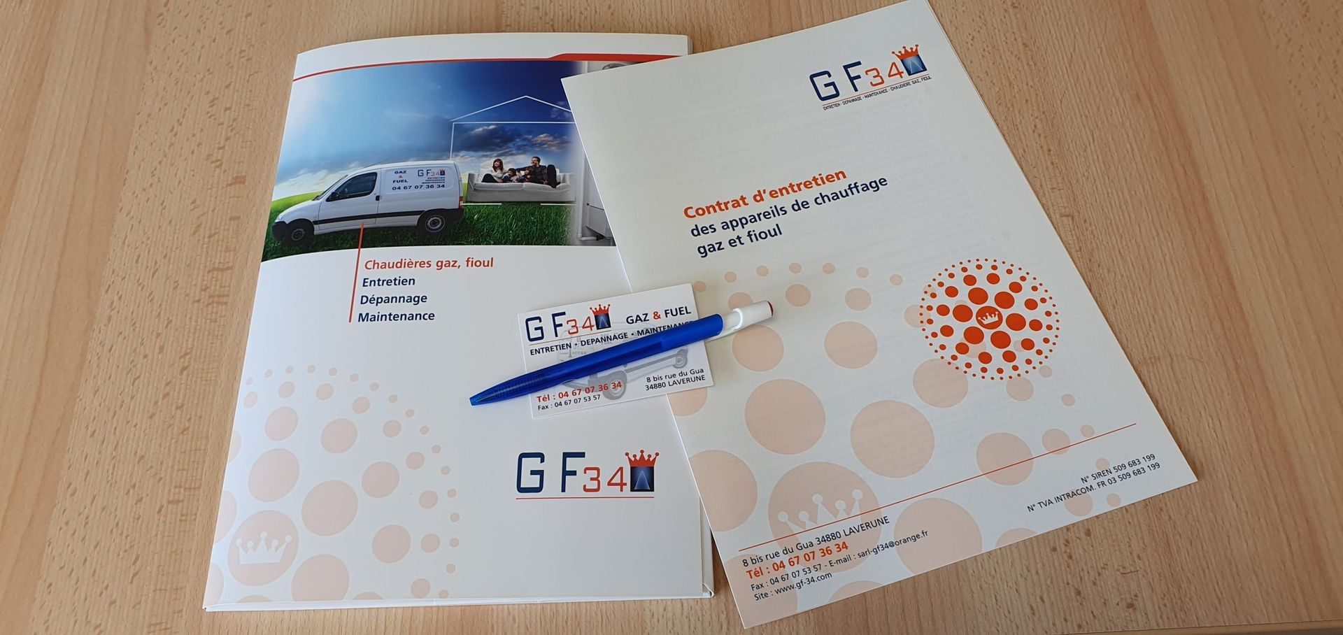 Brochures et stylo sur une surface en bois. Les brochures arborent un logo avec les lettres « G Fari ».