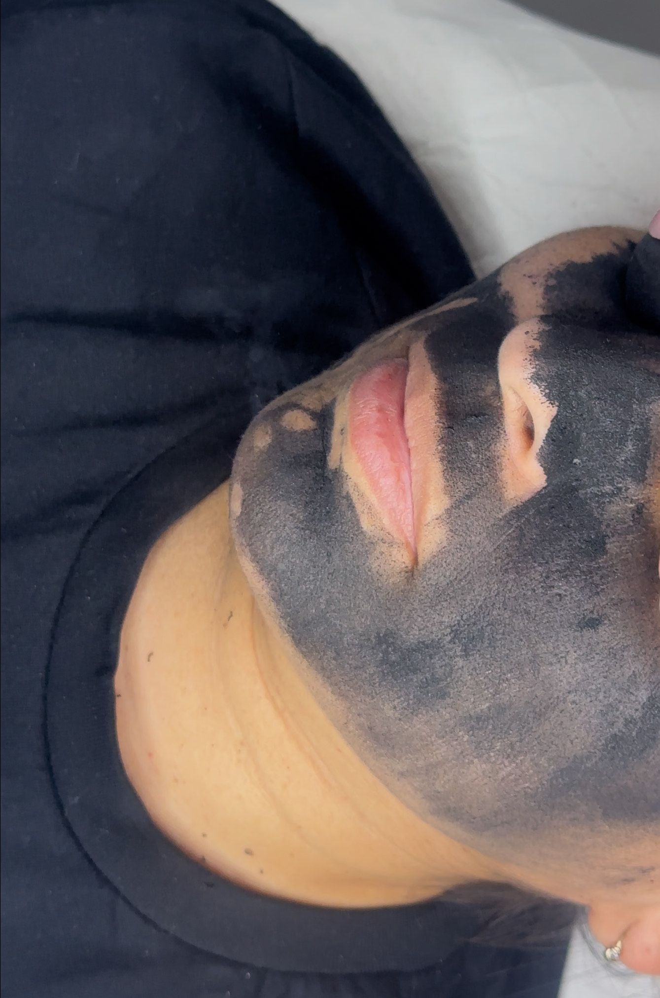 Persona con mascarilla negra; boca rosada y expuesta.