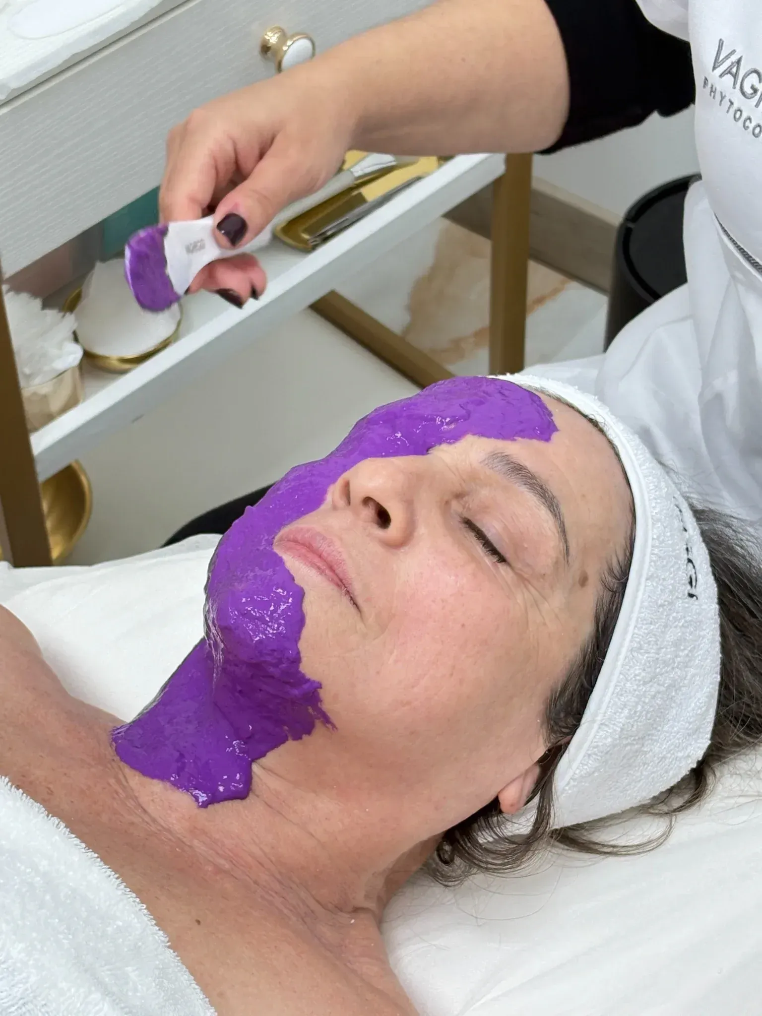 Una mujer se pone una máscara morada en la cara.