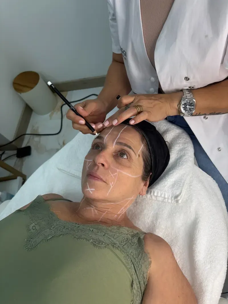 Una mujer está acostada en una cama recibiendo un tratamiento facial.