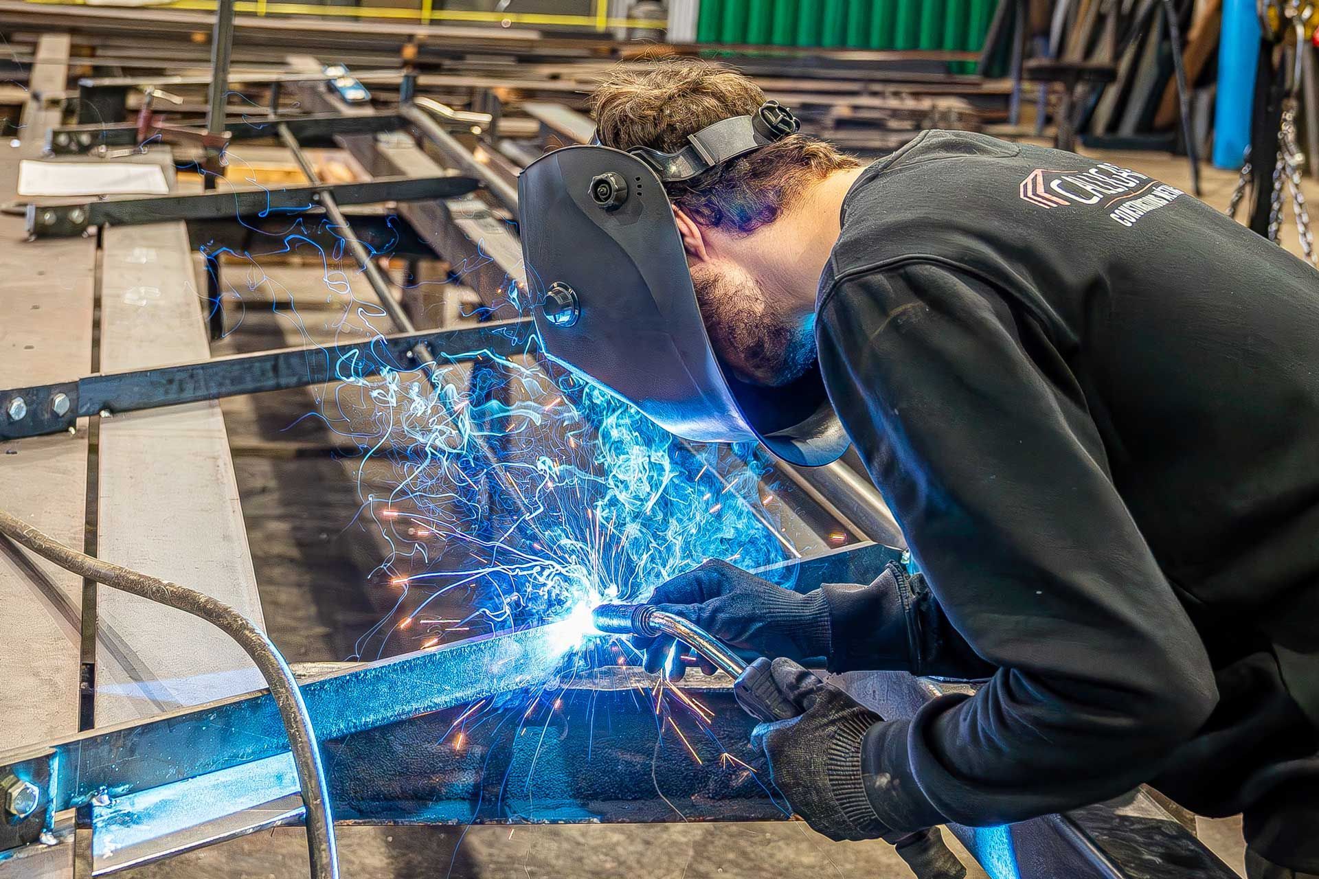 Professionnel soudant une pièce métallique en atelier