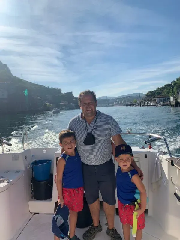 Un hombre y dos niños están de pie en la parte trasera de un barco.