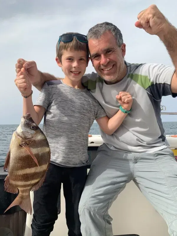 Un hombre y un niño sostienen un pez en un bote.