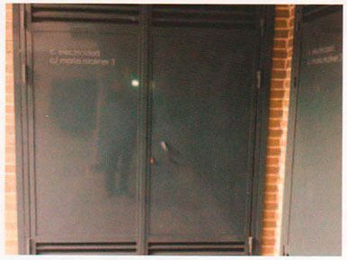 Puertas dobles de cristal con marcos de metal oscuro y una pared de ladrillos a su lado.