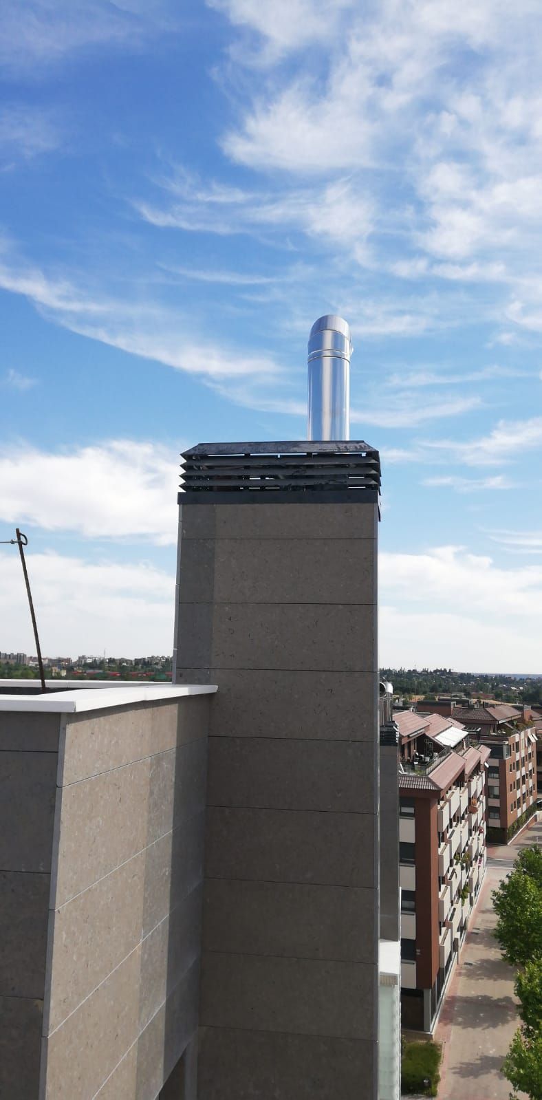 Chimenea en la azotea contra un cielo azul sobre edificios de apartamentos