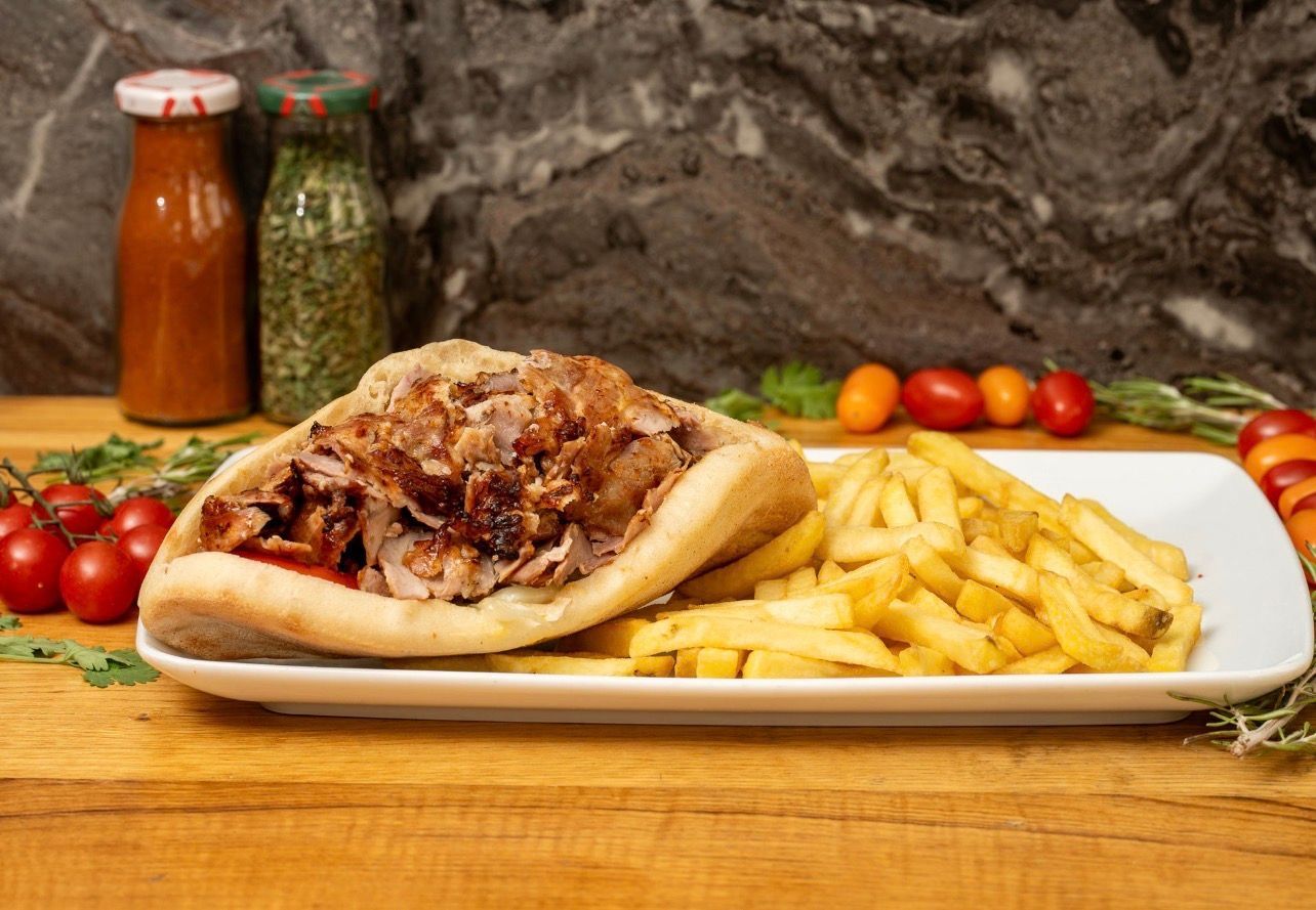 Un long sandwich garni de viande tranchée et de fromage fondu, accompagné d'une grande portion de frites, de mayonnaise et de ketchup.