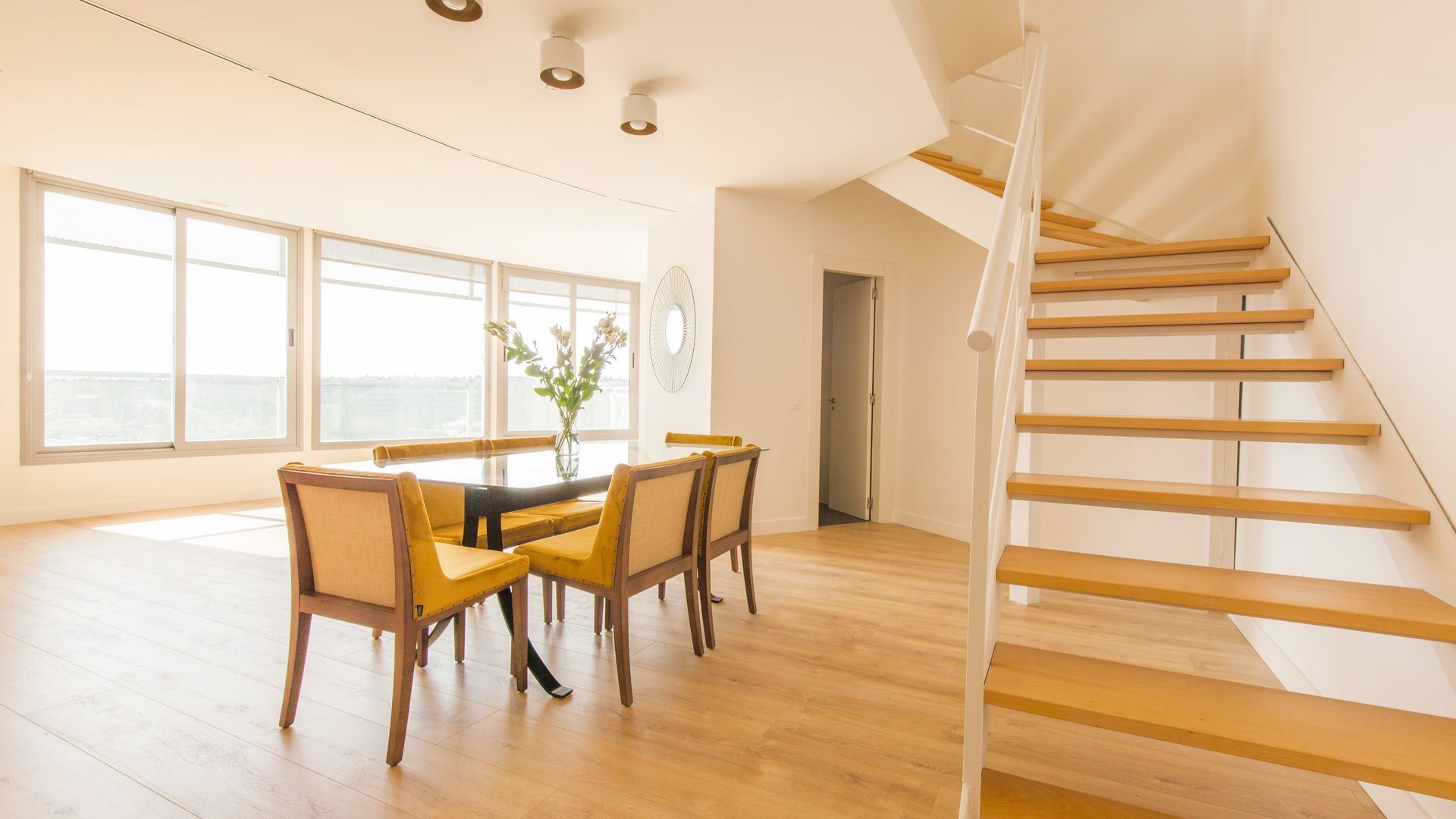 Un comedor con mesa y sillas y una escalera de caracol que conduce al segundo piso.