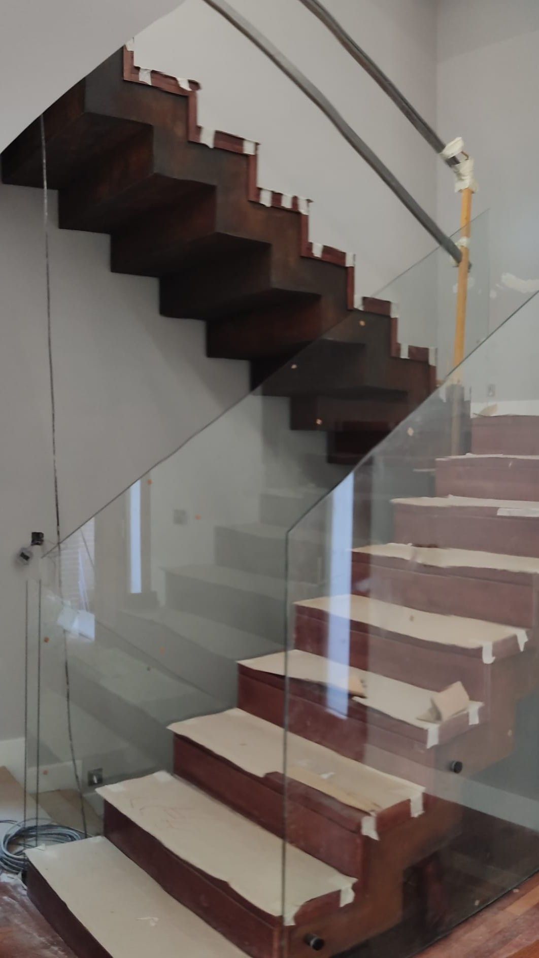 Una escalera de madera con barandilla de cristal en una casa.