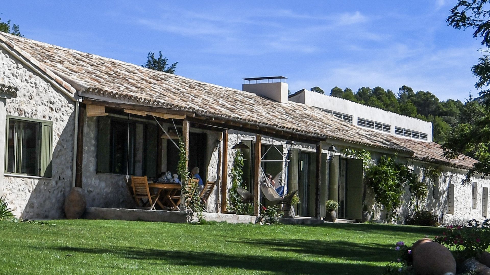 Una gran casa de piedra con techo de tejas y un gran césped delante de ella.