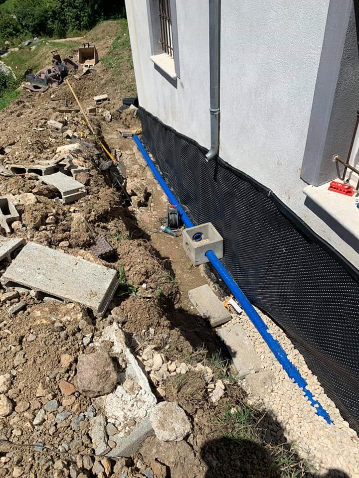 Un mur extérieur peint à moitié en noir et un tuyau bleu qui le longe