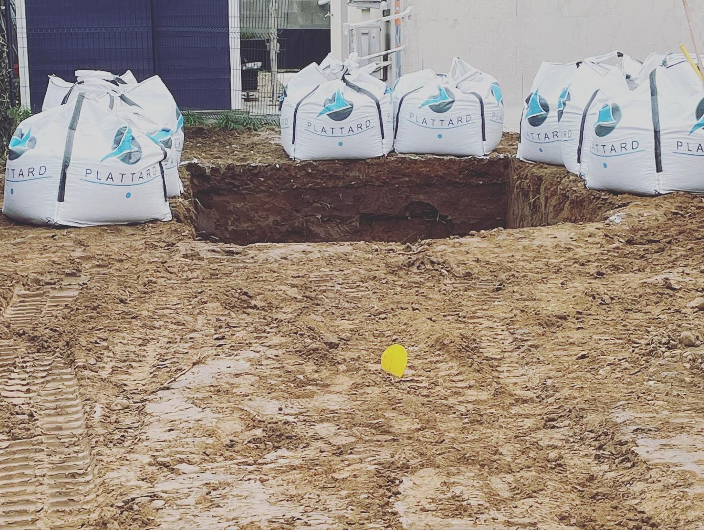 Un trou creusé pour une piscine entouré de sacs de gravats