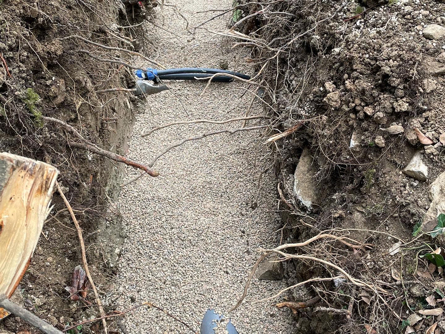 Rigole creusée et remblayée de graviers, un tuyau la traverse