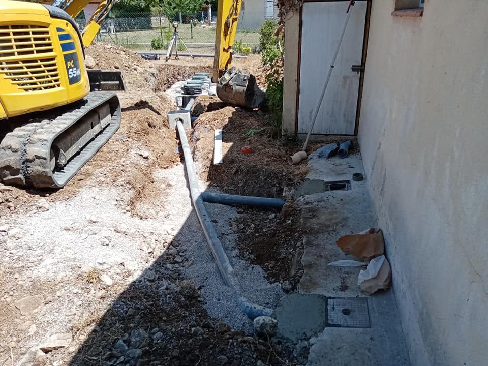 Le long d'un mur : une grue jaune et des tuyaux gris enterrés