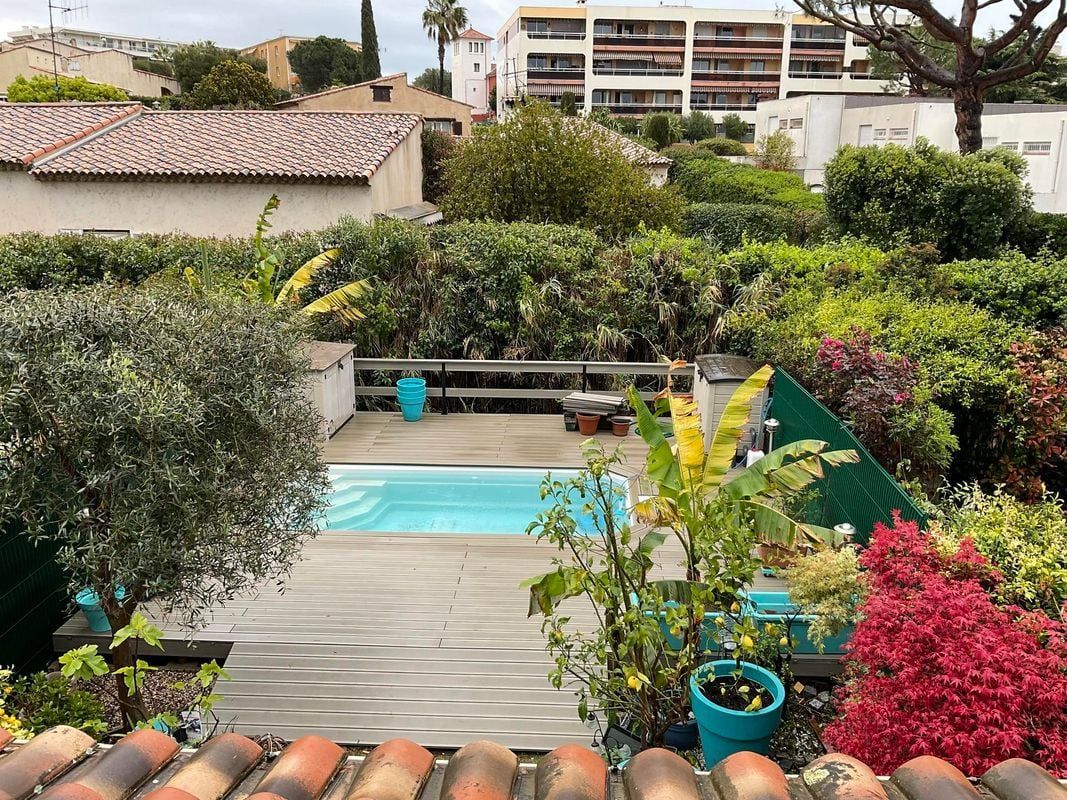 Une terrasse en bois avec une piscine, entourée de verdure