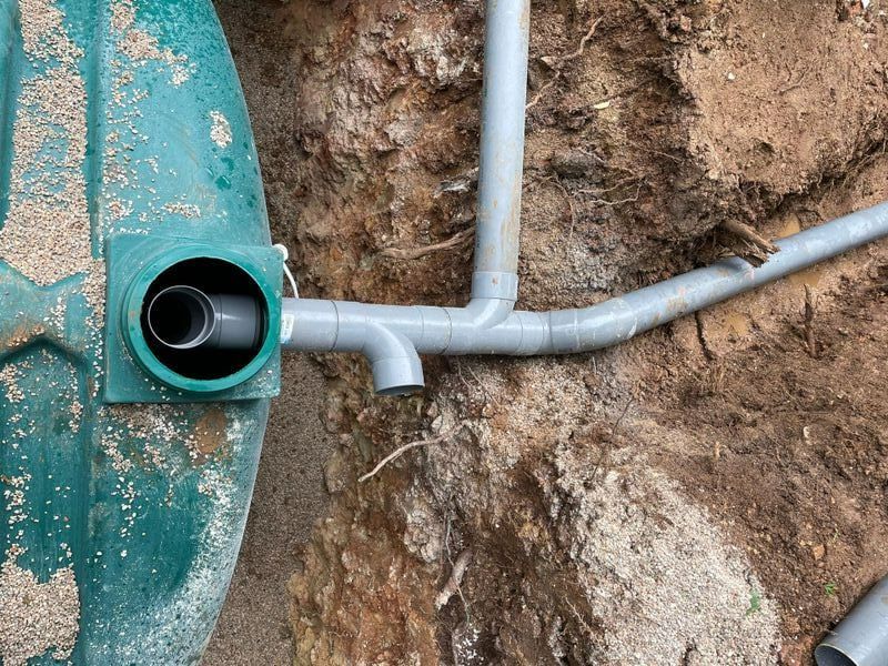 Des tuyaux reliés à une cuve verte dans la terre