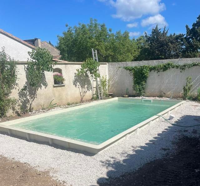 Une piscine à coque posée et entourée de graviers