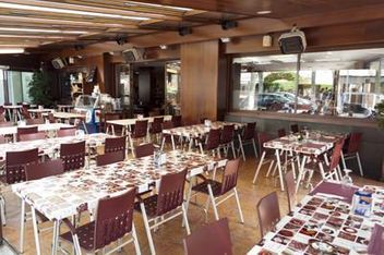 Un comedor interior con filas de mesas cubiertas con manteles estampados y sillas a juego, situado bajo un techo de madera.