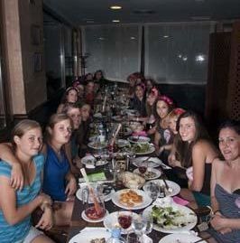 Un grupo de personas sentadas en una mesa larga en un restaurante con poca luz, disfrutando de una comida juntos.