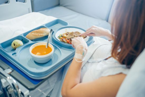 Frau isst im Krankenhausbett