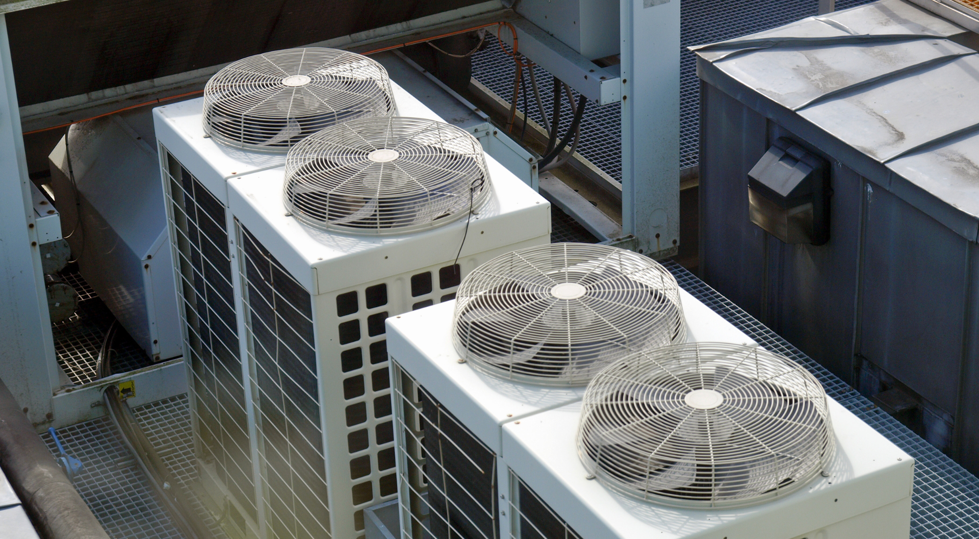 Cuatro unidades de aire acondicionado en la azotea con cubiertas protectoras para los ventiladores.