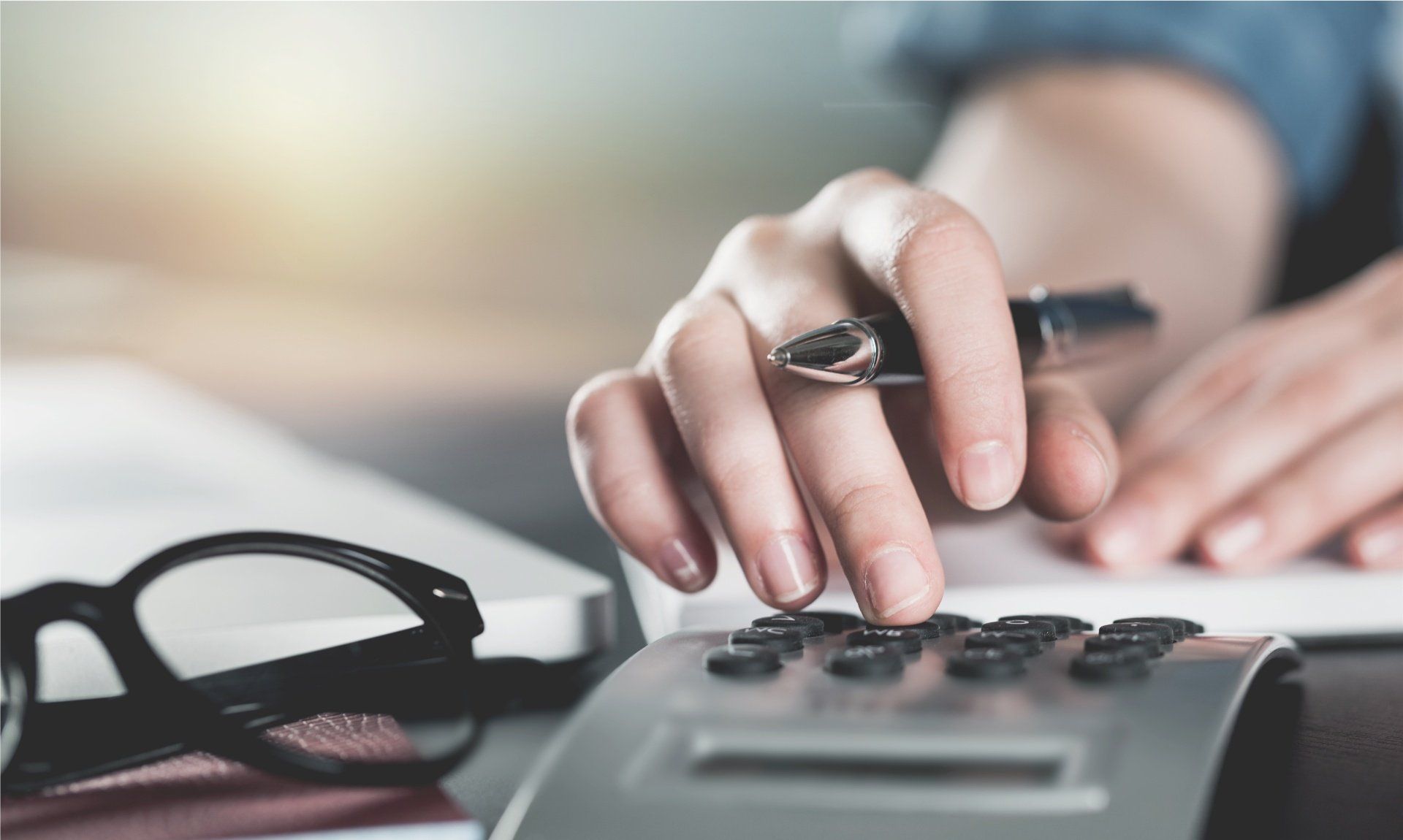 Main qui tient un stylo et tape sur une calculatrice